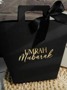 Set de 5 bolsas de regalo Umrah Mubarak en colores azul marino, negro y blanco con diseño de lámina dorada y cintas de satén. Perfectas para almacenar caramelos, chocolates y pequeños regalos. Ideal para celebraciones de Umrah, Eid y ocasiones especiales. ¡Elegante empaque para experiencias de regalo memorables! - 9.5X8X12.5cm - Ver 5