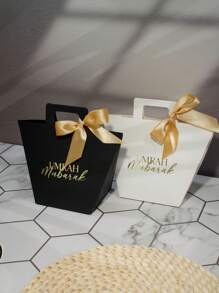 Set de 5 bolsas de regalo Umrah Mubarak en colores azul marino, negro y blanco con diseño de lámina dorada y cintas de satén. Perfectas para almacenar caramelos, chocolates y pequeños regalos. Ideal para celebraciones de Umrah, Eid y ocasiones especiales. ¡Elegante empaque para experiencias de regalo memorables! - 9.5X8X12.5cm - Ver 4