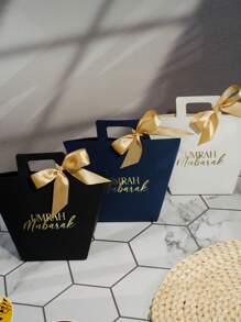 Set de 5 bolsas de regalo Umrah Mubarak en colores azul marino, negro y blanco con diseño de lámina dorada y cintas de satén. Perfectas para almacenar caramelos, chocolates y pequeños regalos. Ideal para celebraciones de Umrah, Eid y ocasiones especiales. ¡Elegante empaque para experiencias de regalo memorables! - 9.5X8X12.5cm - Ver 2