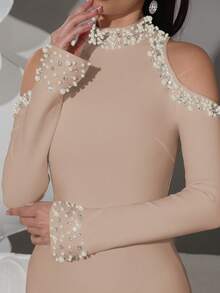 Vestido longo preto elegante com gola alta e ombros à mostra, mangas adornadas com pérolas e strass, modelo justo ao corpo, ideal para festas e casamentos.