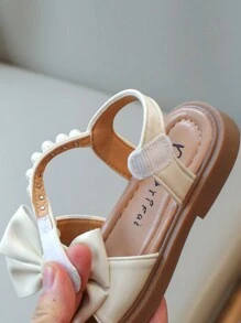 Nuevas sandalias planas para niños, sandalias de princesa coreana para bebés con diseño de lazo de perlas en la suela suave y antideslizante, uso casual y cómodo para el verano