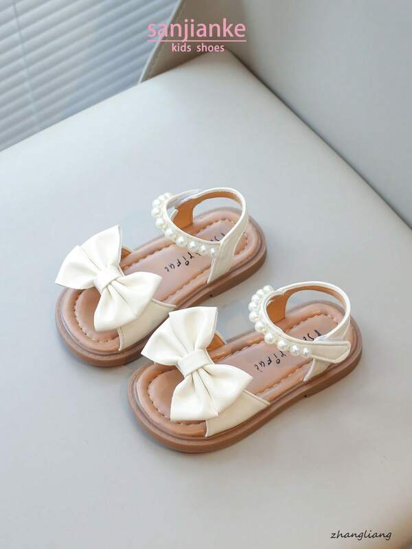 Nuevas sandalias planas para niños, sandalias de princesa coreana para bebés con diseño de lazo de perlas en la suela suave y antideslizante, uso casual y cómodo para el verano
