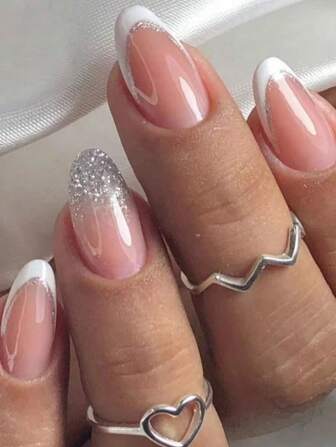 24片装，瞬间提升您的美甲档次！杏仁形假指甲，法式白色设计，点缀银色闪粉，内含1个指甲锉和1张指甲胶贴，是送给女孩、母亲和女性的绝佳礼物。这款美甲套装包含可卸式按压指甲，适合节日、派对、约会和日常佩戴。