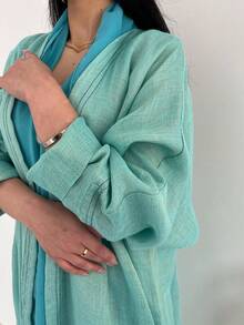 这款时尚简约的女士纯色长袍，搭配时尚优雅的开襟羊毛长袍，充分展现了中东风情，适合日常生活和度假穿着，是一款端庄的卡夫坦长袍。