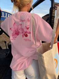 Esta camiseta de cuello redondo con estampado de letras y flores de colores es una opción de moda y versátil para las mujeres en verano. La camiseta gráfica viene en colores blanco y rosa, adecuada para el uso en vacaciones.