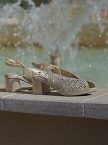 Stile delle calzature. Sandali da donna con tacco a blocco, scollo a V, perforazioni floreali, cinturino posteriore in pelle, con fibbia