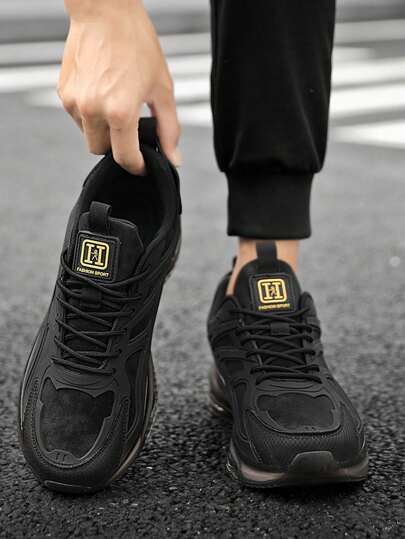 男士科技风街头厚底运动鞋，透气网面系带跑步鞋，黑色和金色点缀，全掌气垫鞋底，提供缓震效果，适合日常休闲穿着。