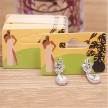 Paquete de 100 piezas de pendientes de gota con diseño de chica guiñando o chica tomando una foto, de 5,5 x 3,5 cm, con tarjeta de embalaje con diseño de patrones