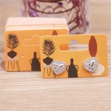 Paquete de 100 piezas de pendientes de gota con diseño de chica guiñando o chica tomando una foto, de 5,5 x 3,5 cm, con tarjeta de embalaje con diseño de patrones