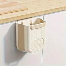 Un organizador de basura de cocina plegable de plástico que se puede colgar en las puertas de los armarios y un contenedor de almacenamiento de clasificación de basura montado en la pared