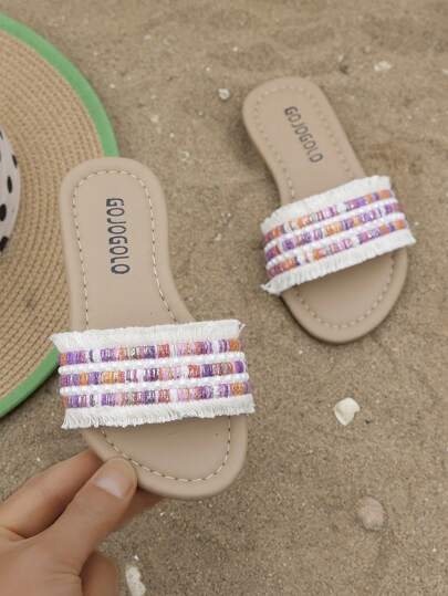 夏季畅销款米色儿童防滑拖鞋，舒适柔软，简约米色平底凉鞋，适合3-12岁女孩，适合室内外日常休闲及海滩穿着。白色编织鞋面，饰以金色和黑色流苏，系带款式。