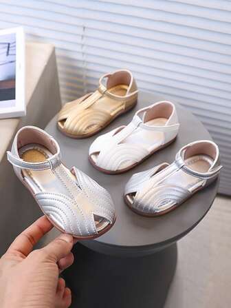 一双适合 2025 年夏季的新款儿童凉鞋。它们是婴儿凉鞋，采用封闭式鞋头设计，鞋底柔软，适合海滩穿着。它们是带有钩环扣的女童鞋。