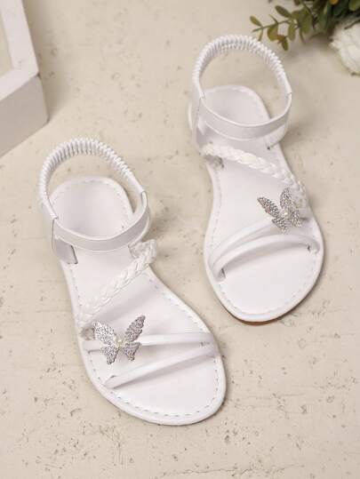 1 par vita plusstorlekar för småbarnsflickor, enfärgade PU-vävda remmar, glänsande färgglad fjärilsdekor, elastisk fotledsrem, rund tå öppen tå, platta halkfria bekväma eleganta söta romerska sandaler, lämpliga för 3-15 år gamla flickor, vardag, casual, fest, resor, vår/sommar 2026