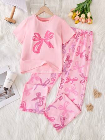 A 2 Pieces Set Of Fashionable Tween Girl Home Clothes, Featuring A Casual Purple Bow Printed Round Neck Short Sleeved Top Paired With A Fully Printed Colorful Bow Patterned Long Pants Set, Creating A Princess Like Look, Suitable For Casual Wear At Home In Spring And Summer