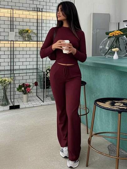 Completo sportivo da donna alla moda per l'autunno, top a maniche lunghe che scopre la pancia, pantaloni a zampa con lacci, aderente