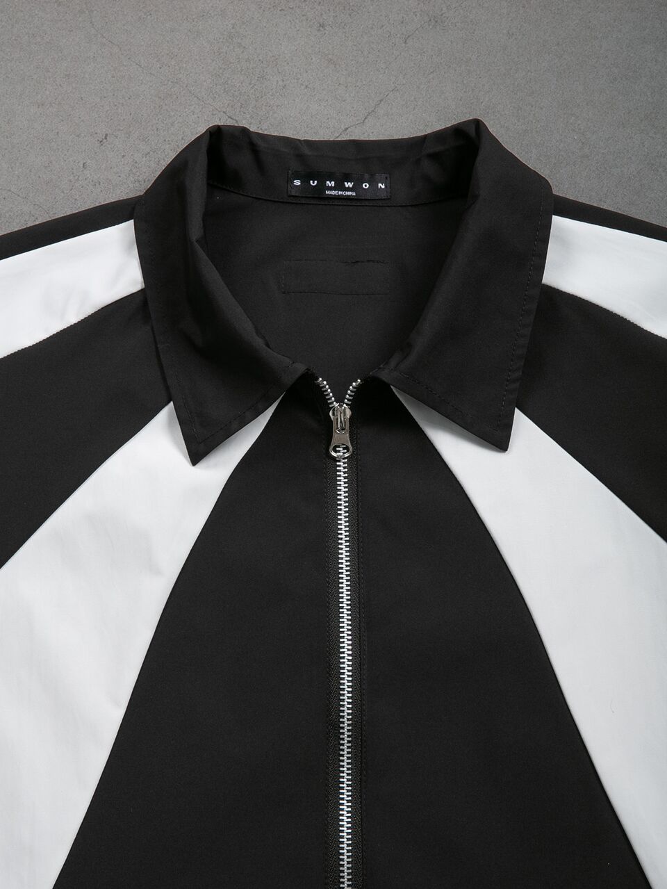 Camicia con colletto e cerniera a maniche corte con blocchi di colore, pannelli neri e bianchi audaci, top statement per festival estivi
