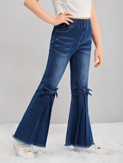 Flickors stora tween-jeans i utsvängd denim, söt rosettdekor, splitfåll med fransad kant, mörktvättad stretchdenim långbyxor, avslappnat vardagsbruk för höst/vinter, moderiktiga tween-kläder
