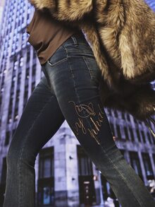 BABYPHAT بنطلون جينز بقصة بوت كات مع شعار مطرز باللون الذهبي ورسمة قطة، خصر منخفض، غسيل داكن، تفاصيل سلسلة، طول كامل - الأزرق - مشاهدة 1