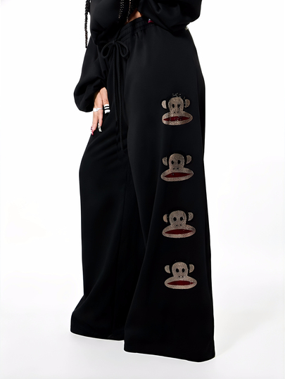 SUMWON X PAUL FRANK SUMWON WOMEN بنطلون جوجر نسائي مطبوع بتصميم كبير، سروال رياضي واسع الساق باللون الأسود، مزين بتطريز قرد بالراين ستون وسحاب للربط، ملابس منزلية كاجوال