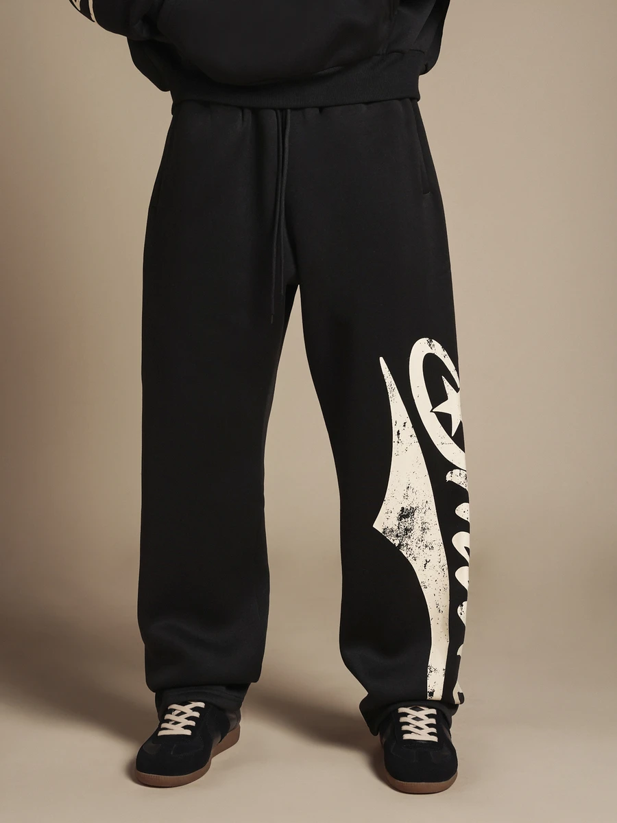 SUMWON Pantalon de jogging en molleton noir à jambes larges avec imprimé logo graffiti surdimensionné sur la jambe, motif étoile et design script crème usé - Noir - Voir 1