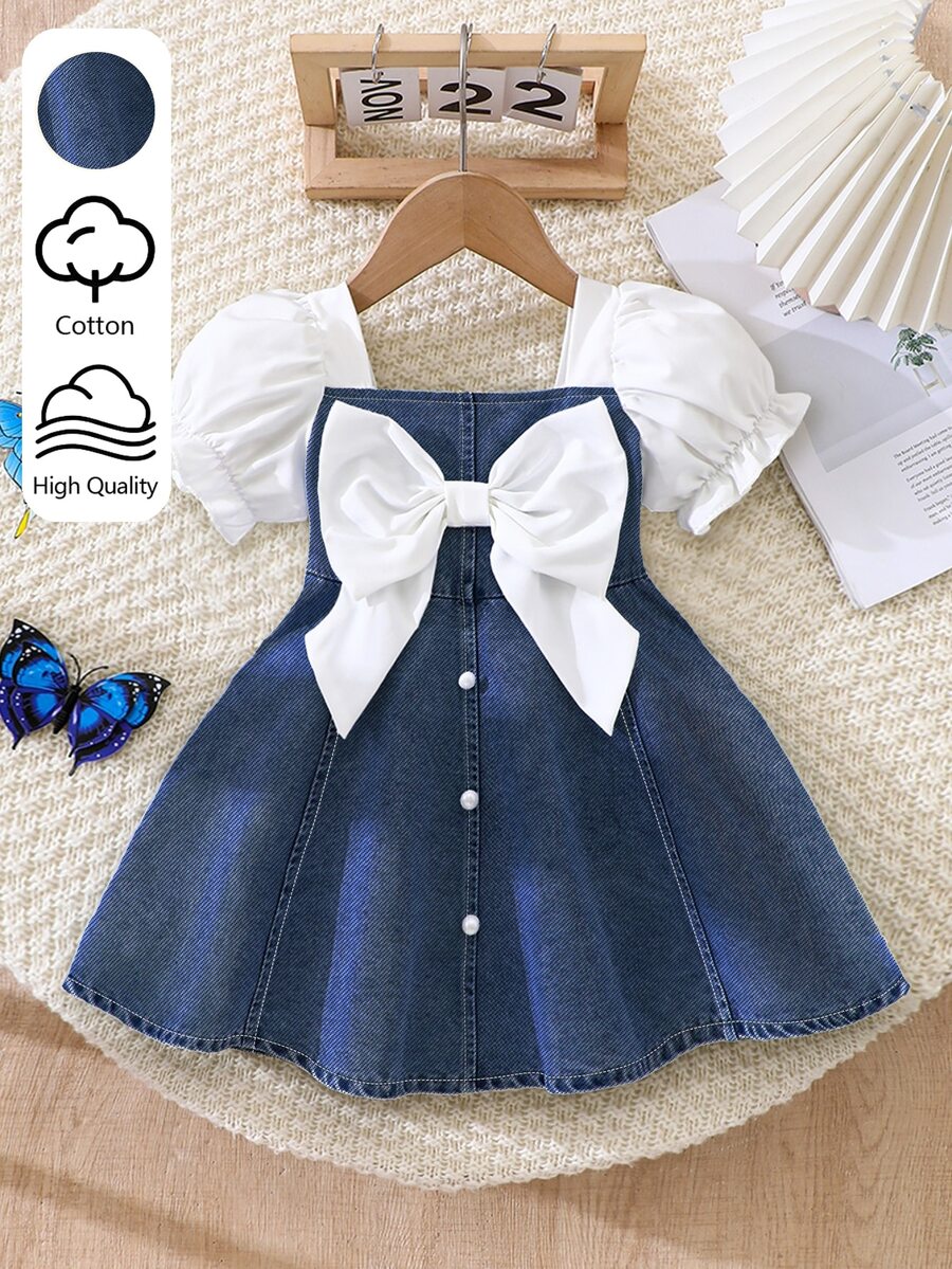 SHEIN Playful Pals 女嬰泡泡袖短袖蝴蝶結牛仔洋裝，方領設計，搭配白色編織布短袖泡泡袖，經典藍色牛仔收腰洋裝，胸前白色大蝴蝶結裝飾，正面優雅精緻白色珍珠裝飾鈕扣，A字裙，適合女嬰可愛俏皮、休閒時尚、舒適通勤穿著，適用日常度假、參加派對與節日，適合派對穿搭、實用時尚、島嶼風、海灘週末、夏季穿著