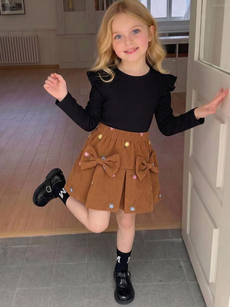 SHEIN Conjunto de 2 piezas para niña pequeña, top de manga larga con volantes de punto acanalado negro y falda de pana marrón con lazo de pompones, ropa linda de otoño/invierno para niña pequeña
