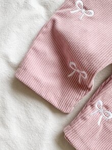 SHEIN 女嬰2件套，包含白色圓領長袖上衣與粉色工裝褲，適合春秋穿著。荷葉邊袖上衣活潑有趣，呈現甜美可愛風格。吊帶褲布滿蝴蝶結圖案，展現清新田園休閒外觀 - 淺粉色 - 查看 9