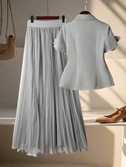 Modelyn Bộ đồ công sở nữ gồm áo tay ngắn cài một nút đơn giản và chân váy xếp ly đính họa tiết 3D, thích hợp cho mùa thu/đông.
