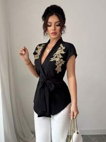 Calvaya Elegante e versatile blusa nera da donna a maniche corte con arricciatura frontale, retro lungo, con rifinizione in pizzo dorato e tessuto non elastico