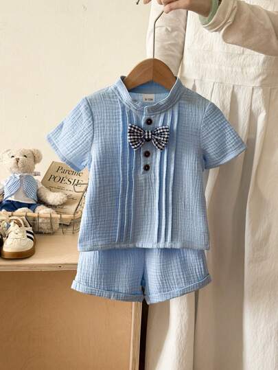 2 件婴幼儿/男童两件套服装，包括 1 件纯色格子蝴蝶结装饰短袖上衣和 1 条松紧腰蓝色梭织短裤，100% 纯棉面料，适合 6 个月至 2-3 岁男婴日常生活、户外活动、休闲装