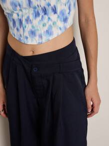 Nöista Pantalon évasé en bleu foncé avec une fermeture à bouton à la taille. Design fluide et élégant, idéal pour ceux qui recherchent le confort et le style. Parfait à porter avec des chemisiers légers ou des hauts ajustés dans un style décontracté et soigné