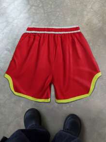 Manfinity EMRG Pantalones cortos deportivos de estilo callejero para hombres, adecuados para el estilo INS, impresos con el lema deportivo "Instant Energy Drive" de alta calle, contraste clásico rojo y amarillo con impresión de letras grandes por ambos lados, perfectos para festivales de música