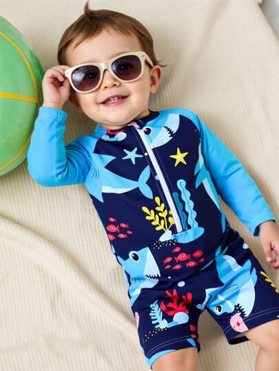 婴儿拉链泳衣，鲨鱼与海洋生物印花。夏季海滩度假必备时尚单品。长袖设计，蓝色撞色，可爱的鲨鱼与海洋生物卡通图案。活泼的设计。适合可爱的男宝宝在海滩玩耍和度假时穿着。