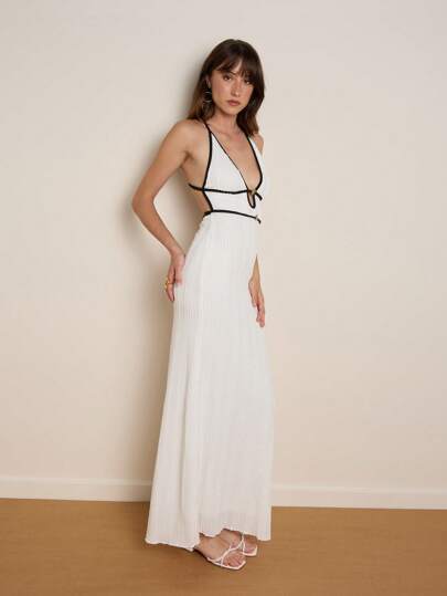 Nöista Langes weißes Kleid mit delikater Textur und elegantem Design, es verfügt über einen tiefen Halter-Ausschnitt mit schwarzen Details als Kontrast, sowie eine zentrale goldene Verzierung, die Sophistication und Glamour verleiht. Es ist perfekt, um bei besonderen Anlässen wie Abschluss, eleganten Abendessen oder Galas hervorzustechen und einen modernen und verfeinerten Stil zu zeigen.