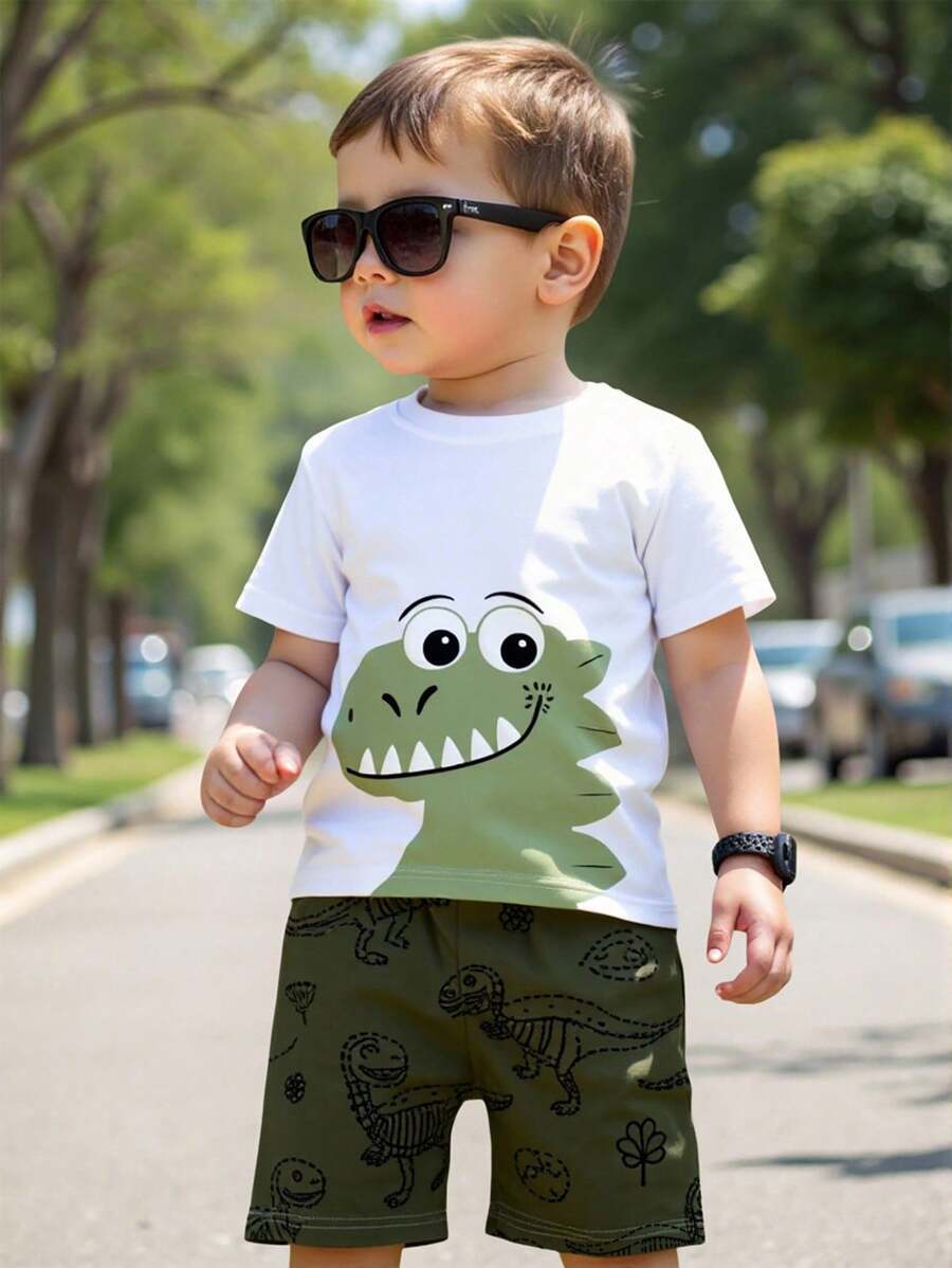 SHEIN Playful Pals 1 Set Toddler Cartoon Style T-Shirt And Shorts Set, T-Shirt With Adorable Green Dinosaur Head Print, Shorts With All-Over Blue Dinosaur And Fossil Pattern, Short Sleeve Shorts, Lightweight, Suitable For Daily Wear, Spring/Summer - Multicolor - View 1