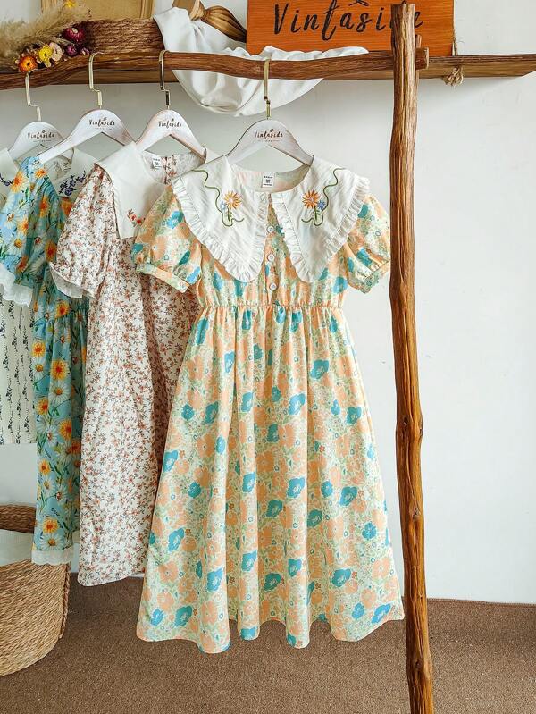 SHEIN Vintaside Kids Robe courte aux manches courtes, col large, brodée et imprimée numériquement, style vacances pour filles. Convient pour les vacances d'été, les sorties à la plage. Les jolies fleurs vous donneront une impression de fraîcheur, très adapté pour le port estival.