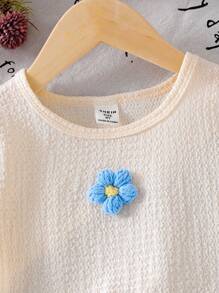 Conjunto de camiseta de textura floral tejida en color albaricoque y shorts con lazo azul para niñas, un conjunto de vestir cómodo y suave de manga corta para el verano