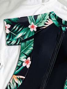 Traje de baño de una pieza con estampado floral para niñas preadolescentes, con cierre de cremallera frontal, manga corta y short negro integrado con patrón de flores estampado a los lados, tipo conjunto de dos piezas
