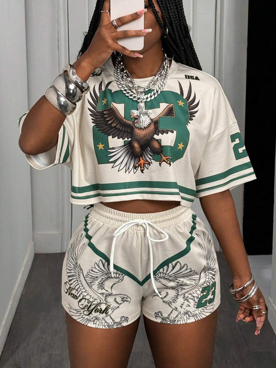 Slaydiva Conjunto deportivo informal de verano 2025 estilo universitario retro: Camiseta de cuello redondo de manga corta con estampado digital de águila 23 y rayas verdes + Pantalón corto estampado con alas y dígitos 23 en color albaricoque, conjunto holgado de dos piezas para mujer