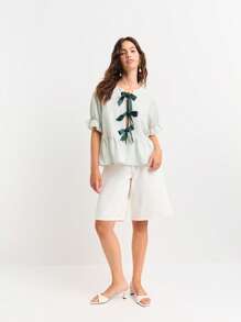 Nöista 条纹荷叶边上衣，短泡泡袖，袖口饰有荷叶边。圆领设计，正面饰有三个蝴蝶结。尽显女性柔美、休闲与优雅。是海滩度假、机场通勤或七月四日休闲装扮的完美之选。 - 綠色 - 查看 4