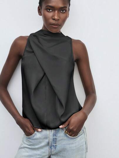 Maija Blusa sin mangas elegante y casual con cuello alto, volantes en la parte delantera, pliegues en la parte trasera y botones. Hecha de tela de satén de alta calidad con textura suave y diseño de pliegues delicados para resaltar el encanto femenino y la moda. Corte holgado sin mangas, cómoda para el trabajo diario, el transporte, las vacaciones y las ocasiones de oficina, también adecuada para fiestas, casual de negocios y otros escenarios. Disponible en gris y negro, simple y versátil, una prenda esencial en el armario.