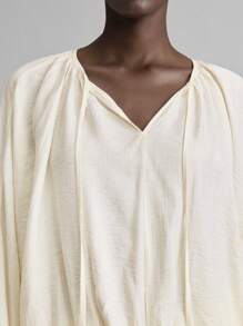 Ontre Áo thun nữ giáo viên thiết kế mới 2025 Ngày Độc lập, mặc thường ngày tại sân bay, chất liệu vải lanh thoải mái, cổ tròn, tay dài, thiết kế thắt nút, thắt eo, bo thun, dáng rộng, mặc hàng ngày, xuân/hè - Màu be - Xem 4