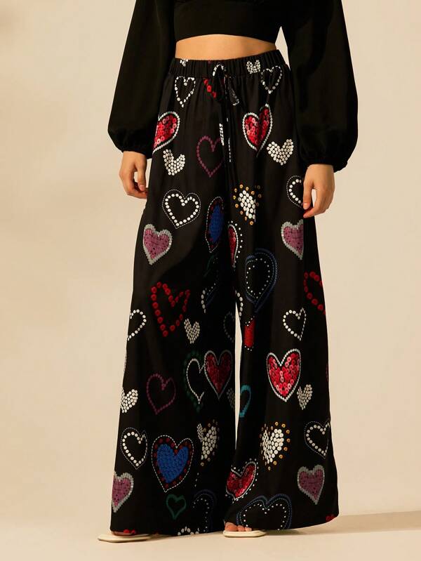 CAJUNI Pantalones sueltos y de moda con cintura ajustada, base negra y estampado de corazones de colores para vacaciones en la playa de verano, con estilo bohemio tropical
