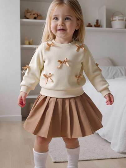 SHEIN Playful Pals 女婴两件套休闲甜美风格，黄色长袖运动衫搭配桃色蝴蝶结装饰和浅棕色百褶裙，适合日常穿着、上学、拍照、聚会、春秋季