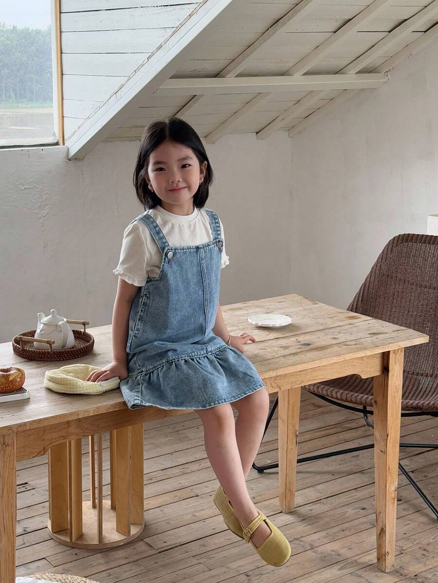 SHEIN 年轻女孩休闲日常简约牛仔吊带裙。柔软棉质牛仔布A字形吊带裙。方形领口，按扣肩带设计。宽大荷叶边下摆。