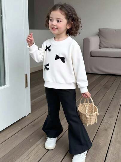 SHEIN Bộ đồ len dệt kim cổ tròn tay dài có nơ trang trí dễ thương cho bé gái và quần len ống loe lưng chun, giản dị và đáng yêu, mùa thu/đông