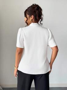 Elenzga 这款优雅的大码白色女式衬衫，领口饰有精致的蝴蝶结，并点缀着柔美的布艺花朵。这款别致的梭织上衣采用时尚的半泡泡袖设计，非常适合办公室或特殊场合穿着。