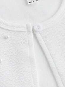 Elegancka kurtka z krótkim rękawem dla nastolatki z teksturowanej dzianiny w kolorze białym z ozdobnymi perłami na ramionach