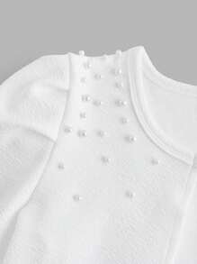 Elegancka kurtka z krótkim rękawem dla nastolatki z teksturowanej dzianiny w kolorze białym z ozdobnymi perłami na ramionach