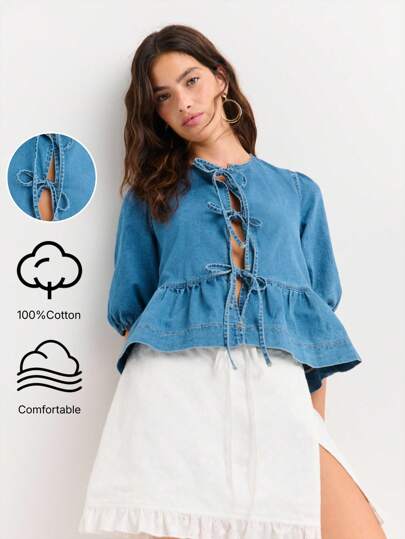 Nöista 经典蓝色牛仔衬衫，泡泡袖，圆领，三道前系带开合，荷叶边下摆。采用柔软棉质牛仔面料制成。关键词：牛仔上衣，泡泡袖，前系带，荷叶边，休闲时尚。